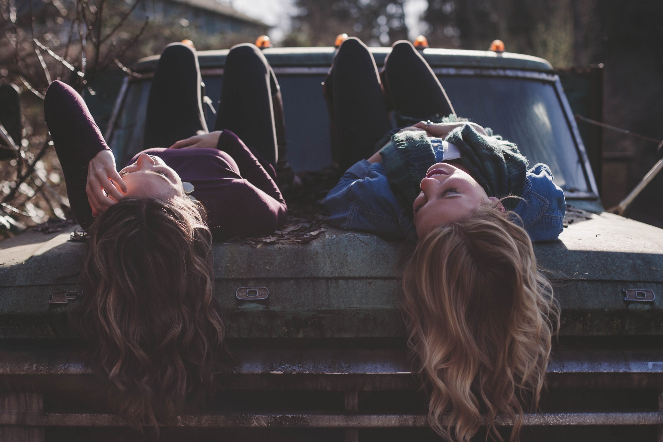 Two women lying on the hood of a truck